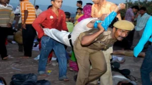 A police officer carries a stampede victim at the Chamunda Devi temple inside the massive 15th century Mehrangarh fort in Jodhpur, India, Tuesday, Sept. 30, 2008. At least 80 people were killed and more than 150 injured when thousands of pilgrims stampeded Tuesday at a Hindu temple in the historic town of Jodhpur in western India, police said..